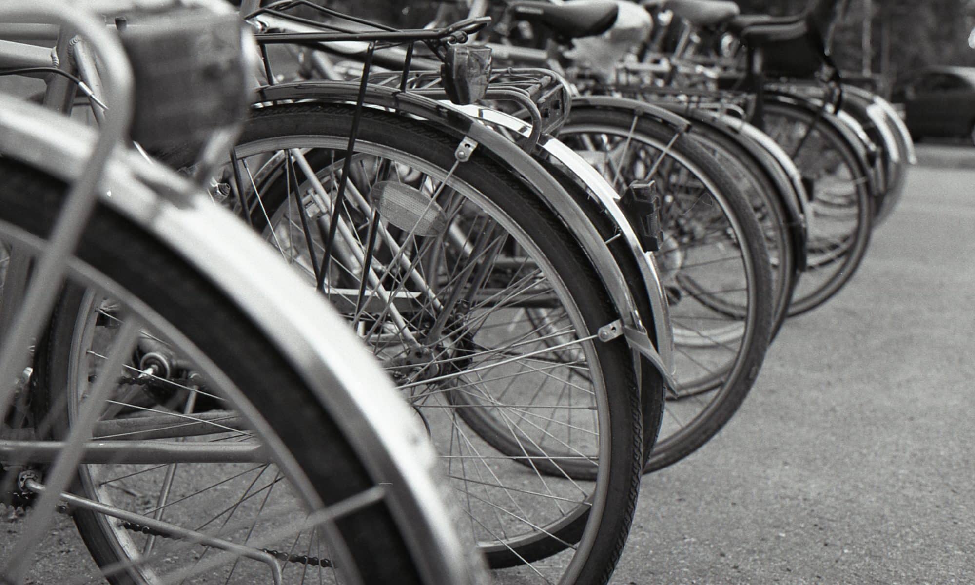 En svartvit bild med parkerade cyklar stående på rad.